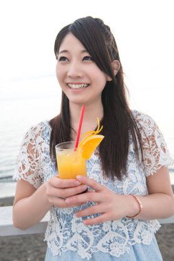 Plajda kokteyl bardağı taşıyan kadın.