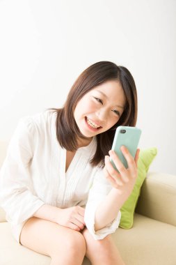 Beyaz üzerine izole edilmiş akıllı telefon kullanan güzel Asyalı bir kadının portresi.