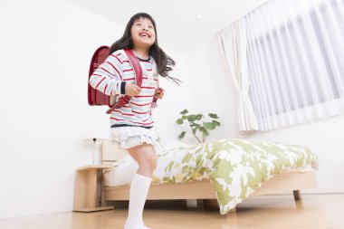 Yatak odasında sırt çantalı güzel bir kız var.