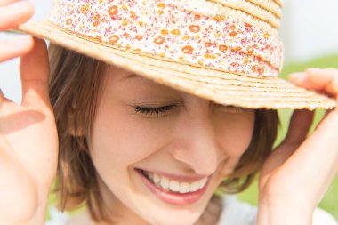 smiling woman wearing straw hat outdoors 