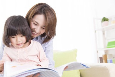 Asyalı anne-kız kitap okuyor. 