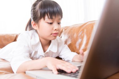 Evde dizüstü bilgisayar kullanan Asyalı genç kız.