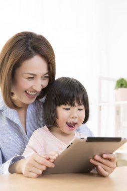 Tablet kullanan Asyalı bir kadın ve bir çocuk.