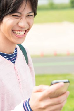 Dışarıda akıllı telefonu olan Asyalı genç bir adam. 