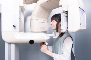 Kadın hasta dişçi tomografisi yapıyor. Dişlerinin röntgenini çeken kadın ortodontik röntgen makinesinin yardımıyla klinikte.