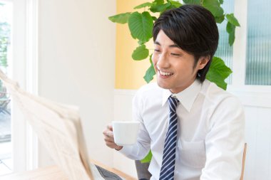 Ofiste gazetesi olan Asyalı bir işadamı.