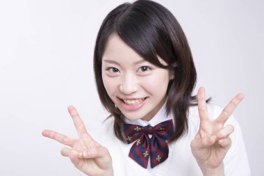 Genç Asyalı öğrenci zafer işaretleri gösteriyor.