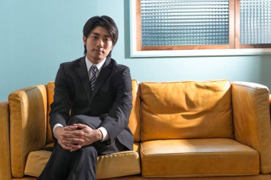 Kanepede oturan Asyalı iş adamı