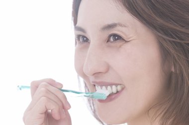 Güzel Japon kadın beyaz arka planda dişlerini fırçalıyor.