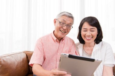 Kanepede tablet kullanan gülümseyen çift.