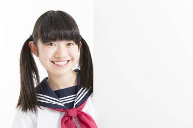 Okul üniformalı güzel bir öğrencinin portresi. Elinde beyaz bir tahta var.