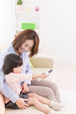 Anne ve kızı evde televizyon seyrediyor.