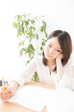 Yorgun Asyalı kadın evde ders çalışıyor.