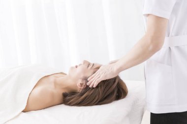 Güzel Japon kadın spa salonunda yüz masajı yaptırıyor.