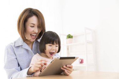 Tablet kullanan Asyalı bir kadın ve bir çocuk.