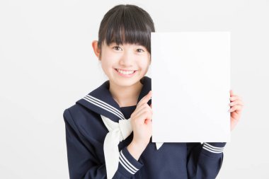 Okul üniformalı güzel bir öğrencinin portresi beyaz arka planda boş bir poster tutuyor.