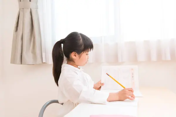 小さなアジアの少女は宿題をしている — ストック写真