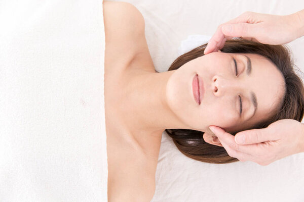 Красивая японская женщина делает массаж лица в спа-салоне