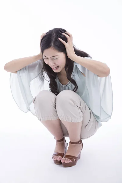 白い背景の上に隔離された床に座って頭痛に苦しんでいる若いアジアの女性 — ストック写真