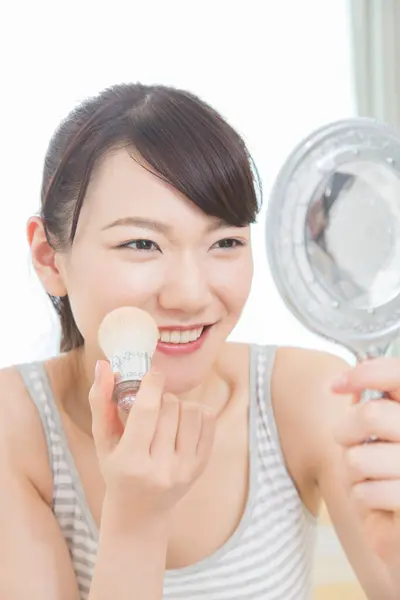 亚洲年轻女子与镜子应用化妆 — 图库照片