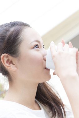 Sıcak kahve içen Asyalı kadını kapat.