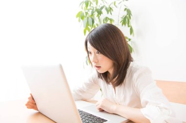 Evde dizüstü bilgisayarda çalışan Asyalı kadın.