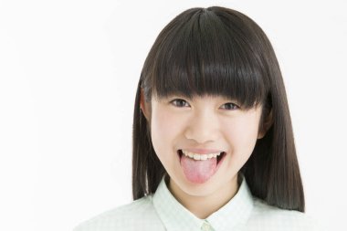 Beyaz arka planda izole edilmiş dil gösteren genç Asyalı kız öğrenci. 