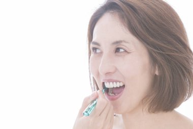 Güzel Japon kadın beyaz arka planda dişlerini fırçalıyor.
