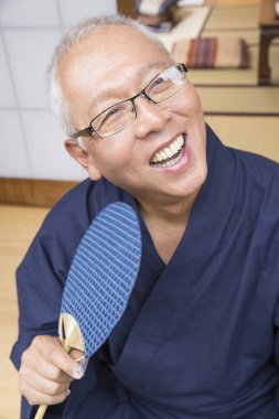 Tahta yelpazeli yaşlı bir Asyalı 'nın portresi.