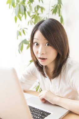 Evde dizüstü bilgisayarda çalışan Asyalı kadın.