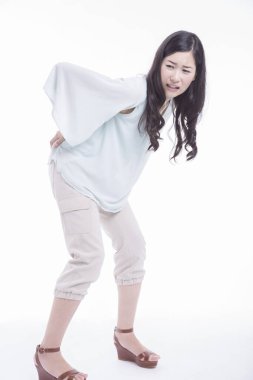 Beyaz arka planda sırt ağrısı olan genç bir kadın.