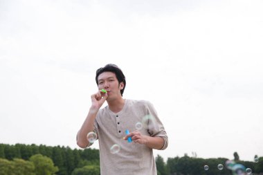 Genç bir adam sabun köpüğüyle oynuyor..