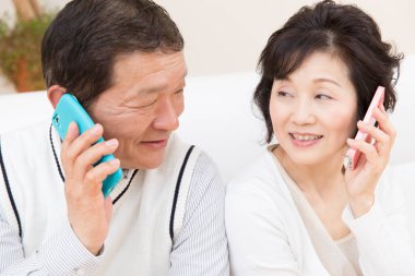 Yetişkin Asyalı çifti telefonları kullanarak kapatın.