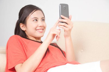 Evde akıllı telefonu olan genç bir kadın.