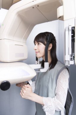 Kadın hasta dişçi tomografisi yapıyor. Dişlerinin röntgenini çeken kadın ortodontik röntgen makinesinin yardımıyla klinikte.
