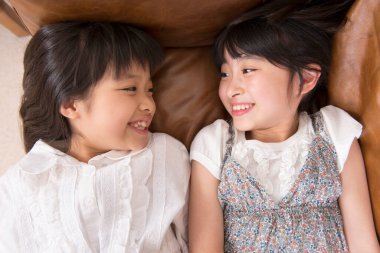 Kanepede yatan Asyalı küçük kız kardeşler.