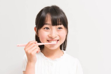 Beyaz arka planda diş fırçalayan Asyalı kız 