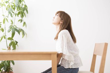 Asyalı kadın oturma odasında masada oturuyor.