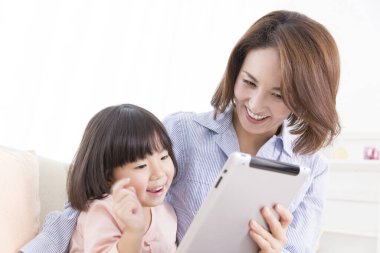 Anne ve kızı evde tablet kullanıyorlar.