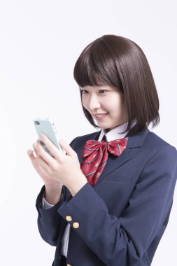 Akıllı telefon kullanan gülümseyen Japon öğrencinin stüdyo portresi