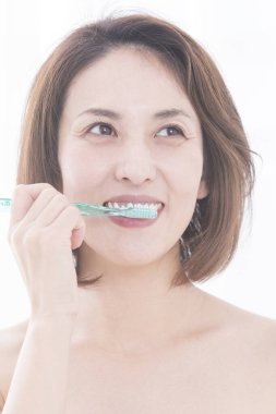 Güzel Japon kadın beyaz arka planda dişlerini fırçalıyor.