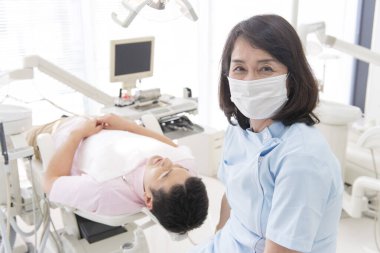 Yatan hastanın yanında maske takan dişçi