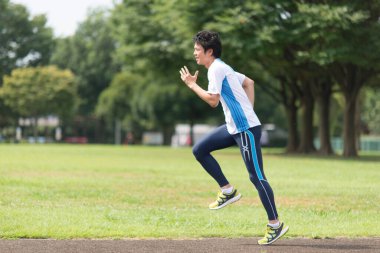 Sportif Japon adam yaz parkında koşuyor. 