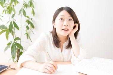 Genç Asyalı kadın evde ders çalışıyor.