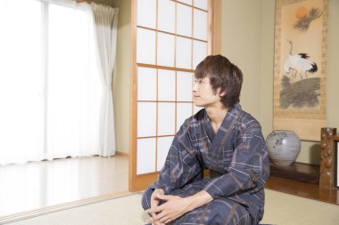 Etnik kaplıca otelinde geleneksel yukata giymiş yakışıklı Japon gencin portresi.