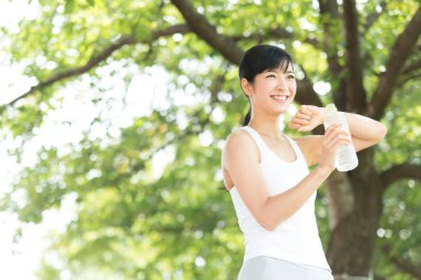 Yaz parkında koşu yaparken su içen güzel Japon kadın. 