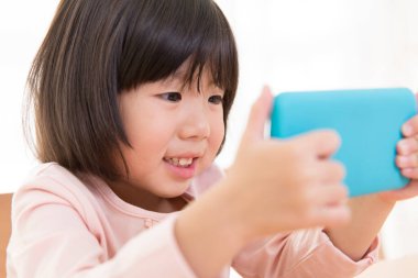 Küçük sevimli Asyalı kız telefon kullanıyor.