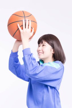 Spor giyim ve basketbol topuyla genç Asyalı kızın stüdyo portresi.