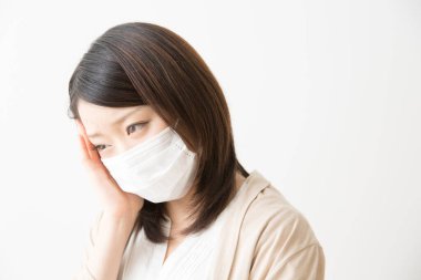 Soluk maskeli hasta bir Asyalı kadının portresi beyaza izole edilmiş.