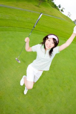 Güzel Asyalı kadın golfçü sahada poz veriyor.